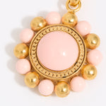 Decorative charm with pink and gold beads on a white background