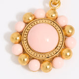 Decorative charm with pink and gold beads on a white background