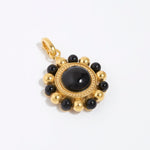 Gold circular charm pendant with central onyx stone with black and gold beaded edge,  on a white background