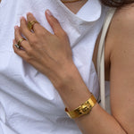 Close-up of a person wearing gold sun cuff bracelet on a white fabric background
