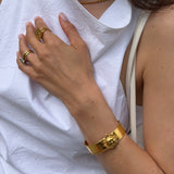 Close-up of a person wearing gold sun cuff bracelet on a white fabric background