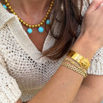 Close-up of a person wearing gold coloured  jewellery with sun cuff