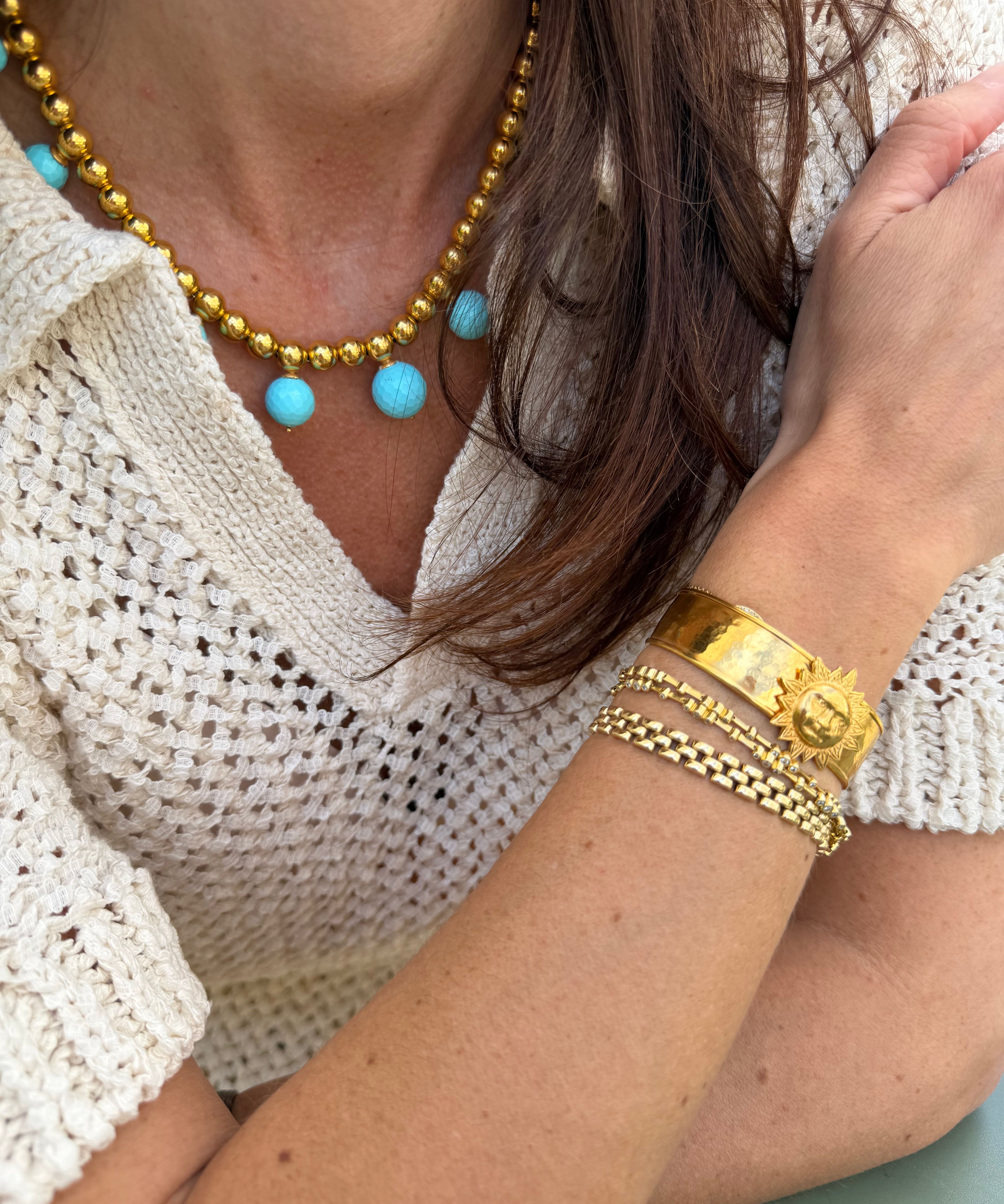 Close-up of a person wearing gold coloured  jewellery with sun cuff