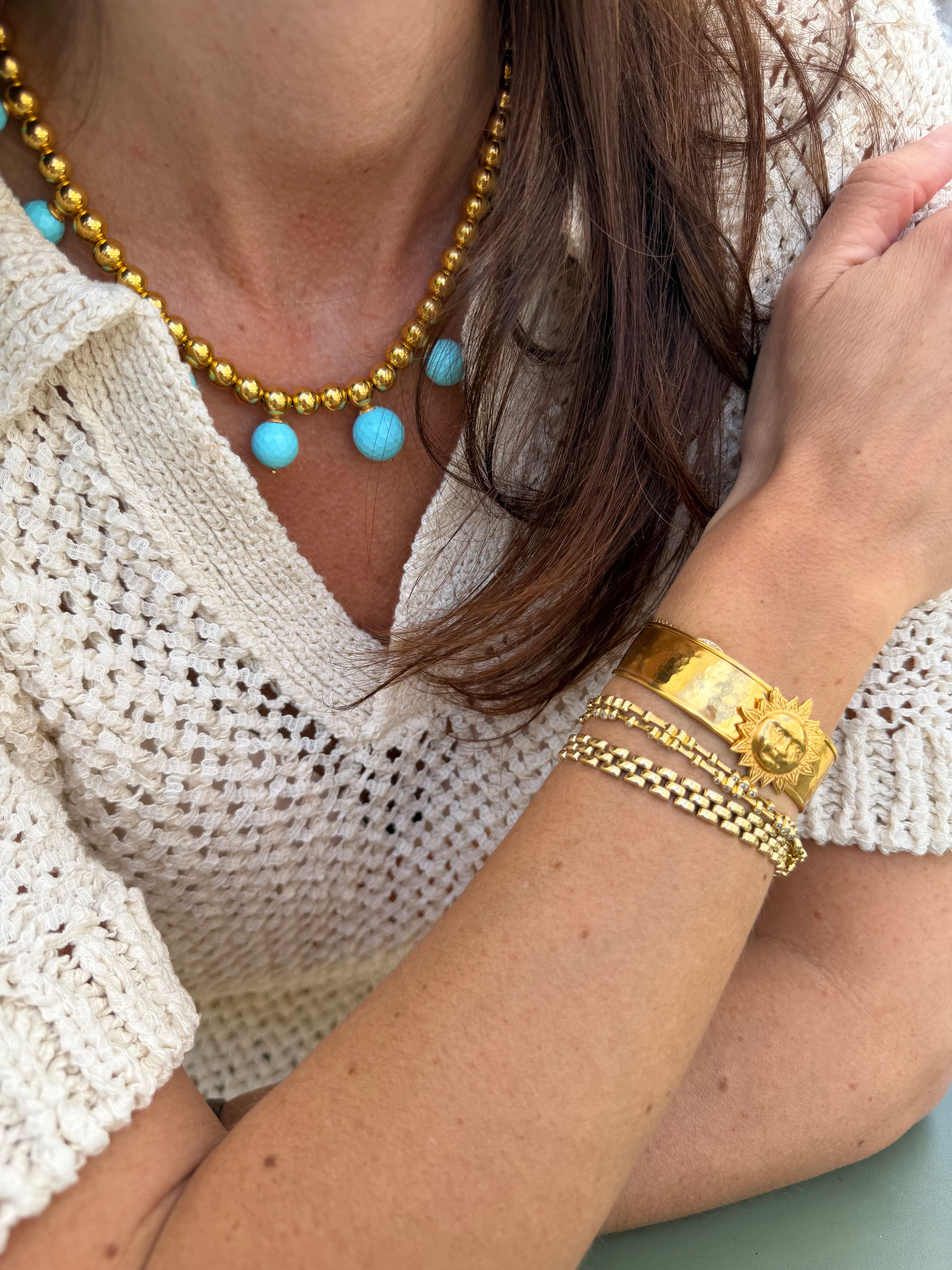 Close-up of a person wearing gold coloured  jewellery with sun cuff