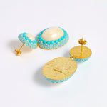 Reverse image of pearl drop earrings with three lines of turquoise coloured matt crystals as a border around the pearls and a gold plated smooth back with post for pierced ears.