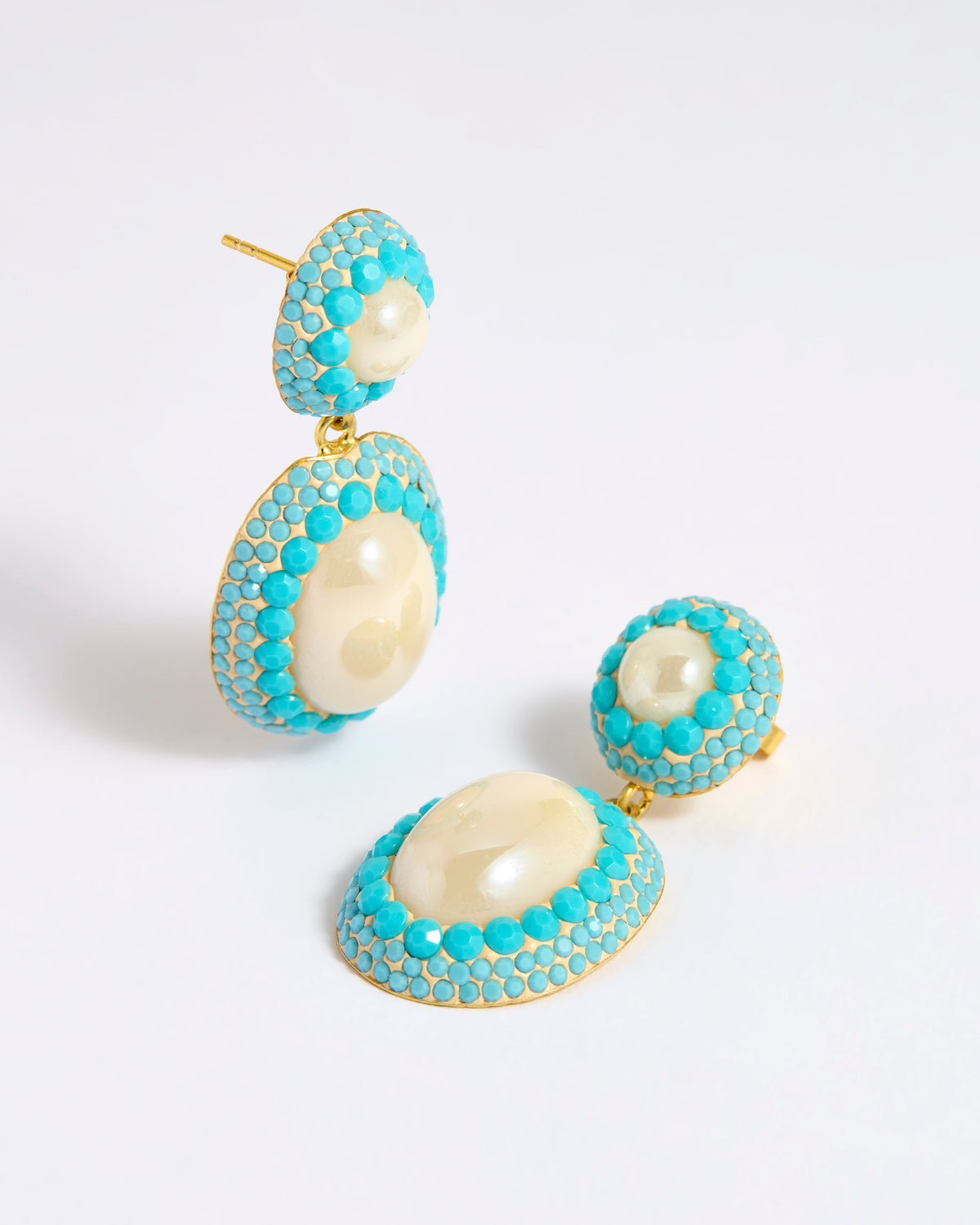 Pearl drop earrings with three lines of turquoise coloured matt crystals as a border around the pearls 