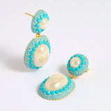 Pearl drop earrings with three lines of turquoise coloured matt crystals as a border around the pearls 