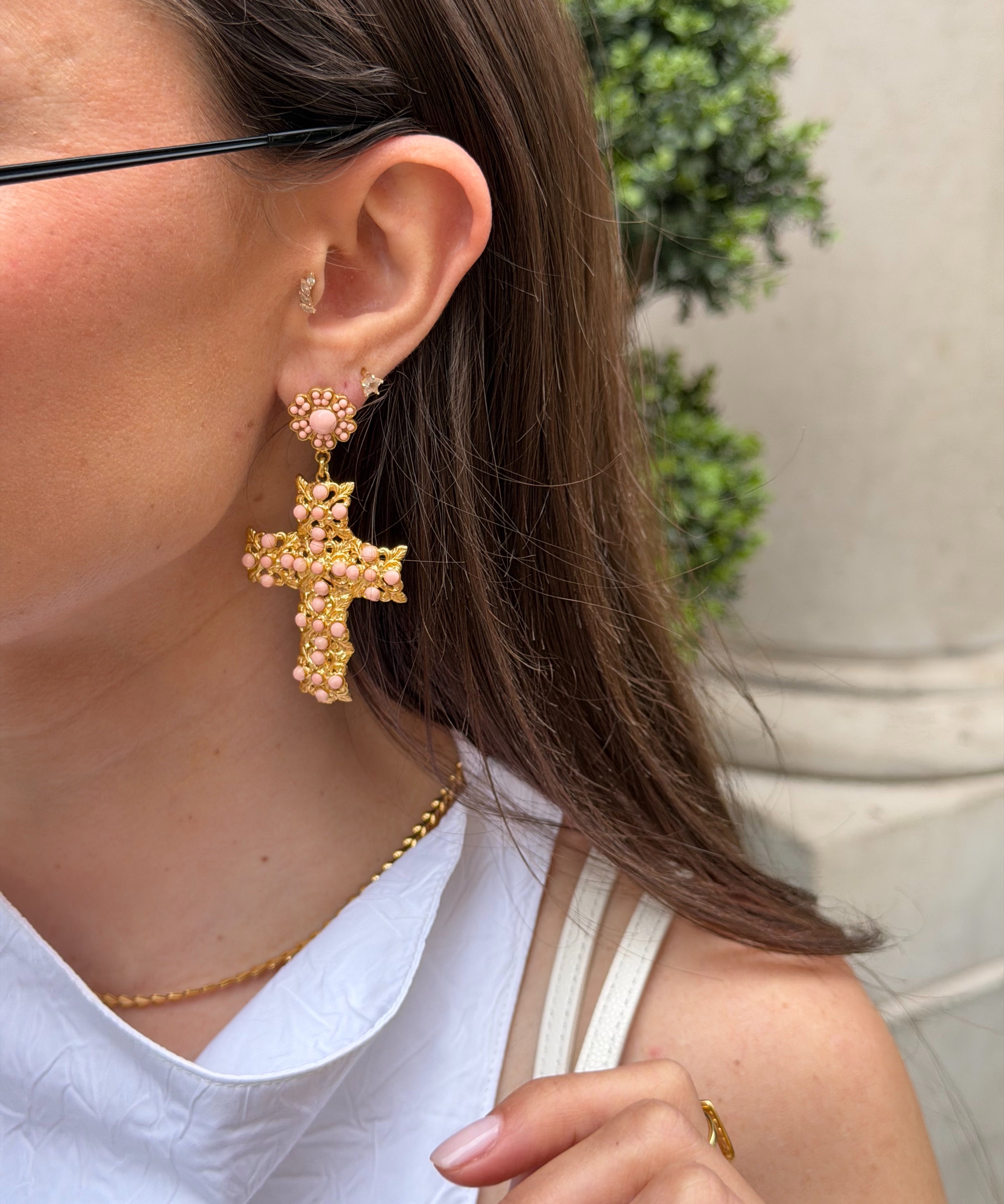 Close-up of a person wearing gold cross earrings 