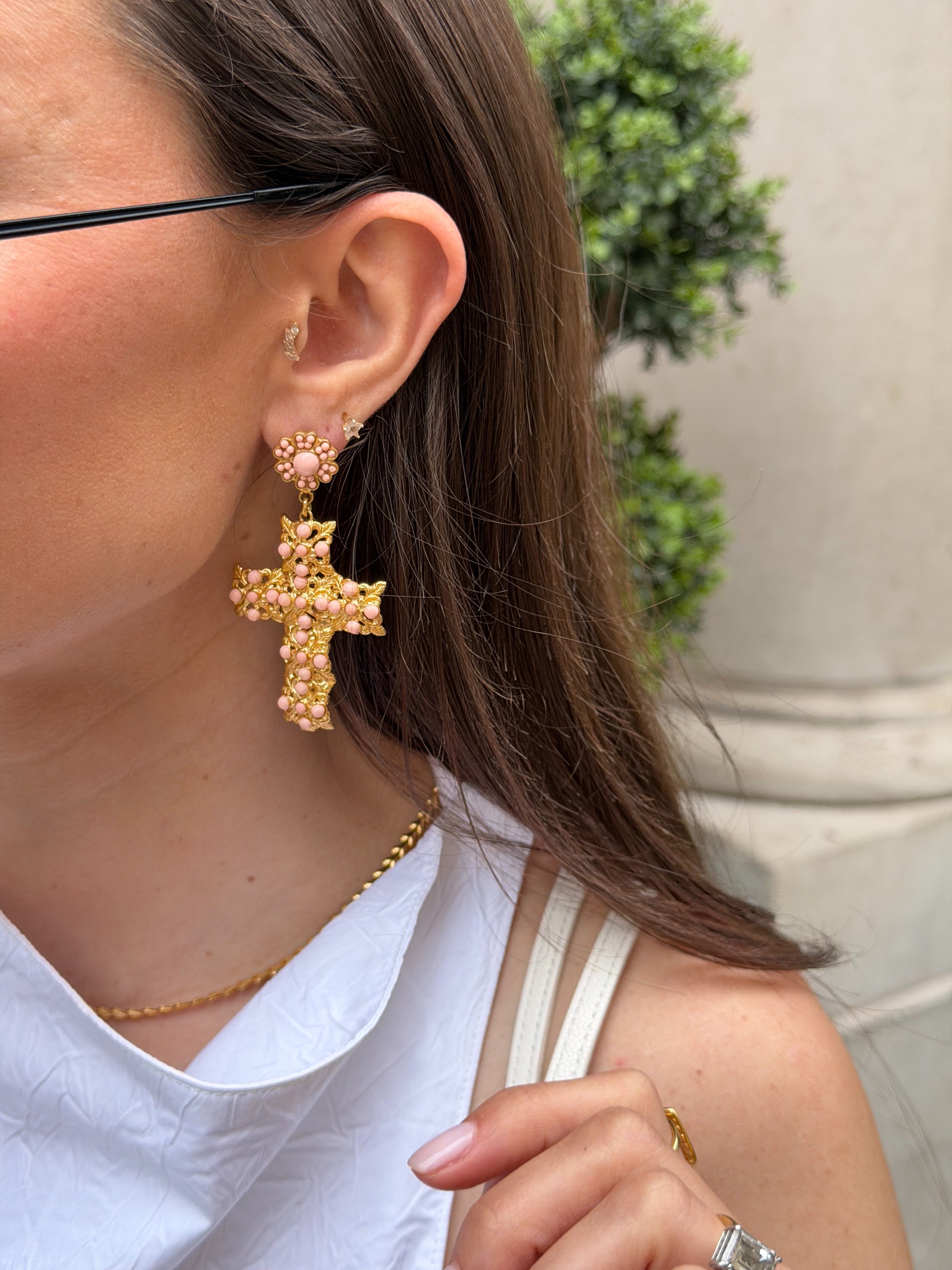 Close-up of a person wearing gold cross earrings 