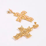 Gold cross-shaped earrings on a white background