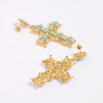 Gold cross-shaped earrings with turquoise stones on a white background