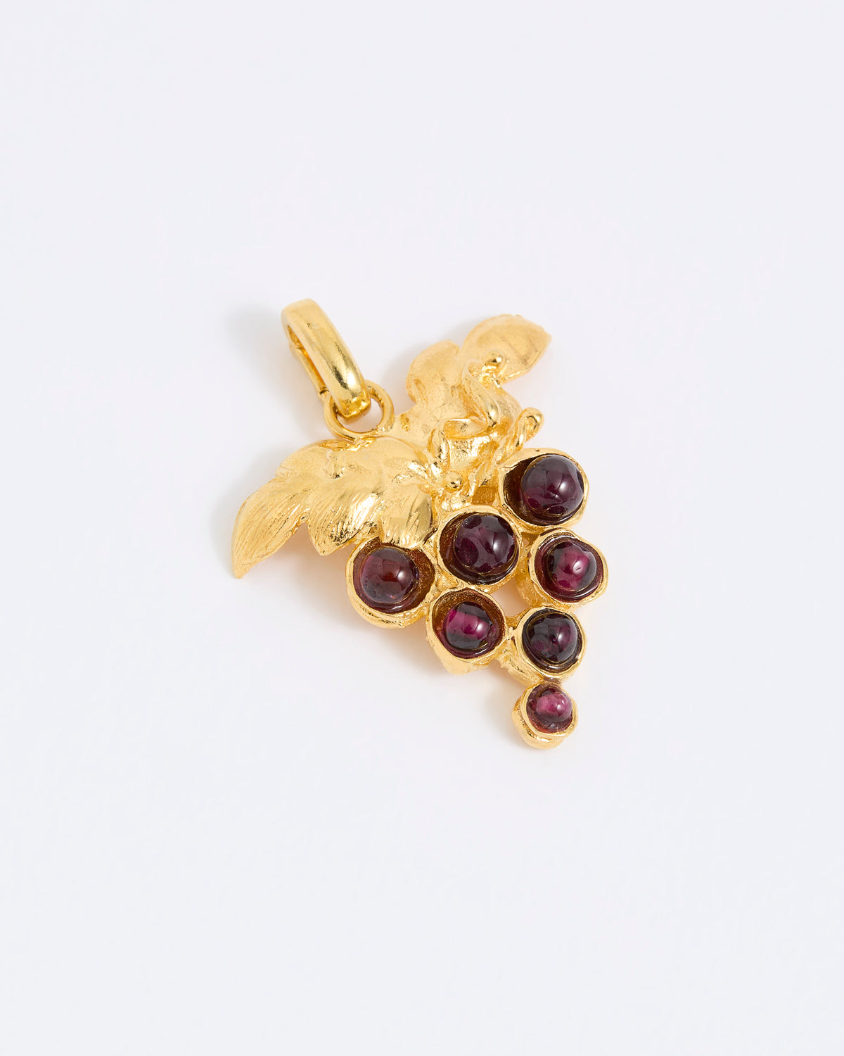 Gold coloured pendant with red gemstones in the shape of a grapevine on a white background