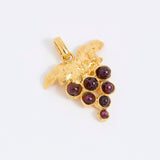 Gold coloured pendant with red gemstones in the shape of a grapevine on a white background