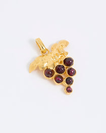Gold coloured pendant with red gemstones in the shape of a grapevine on a white background