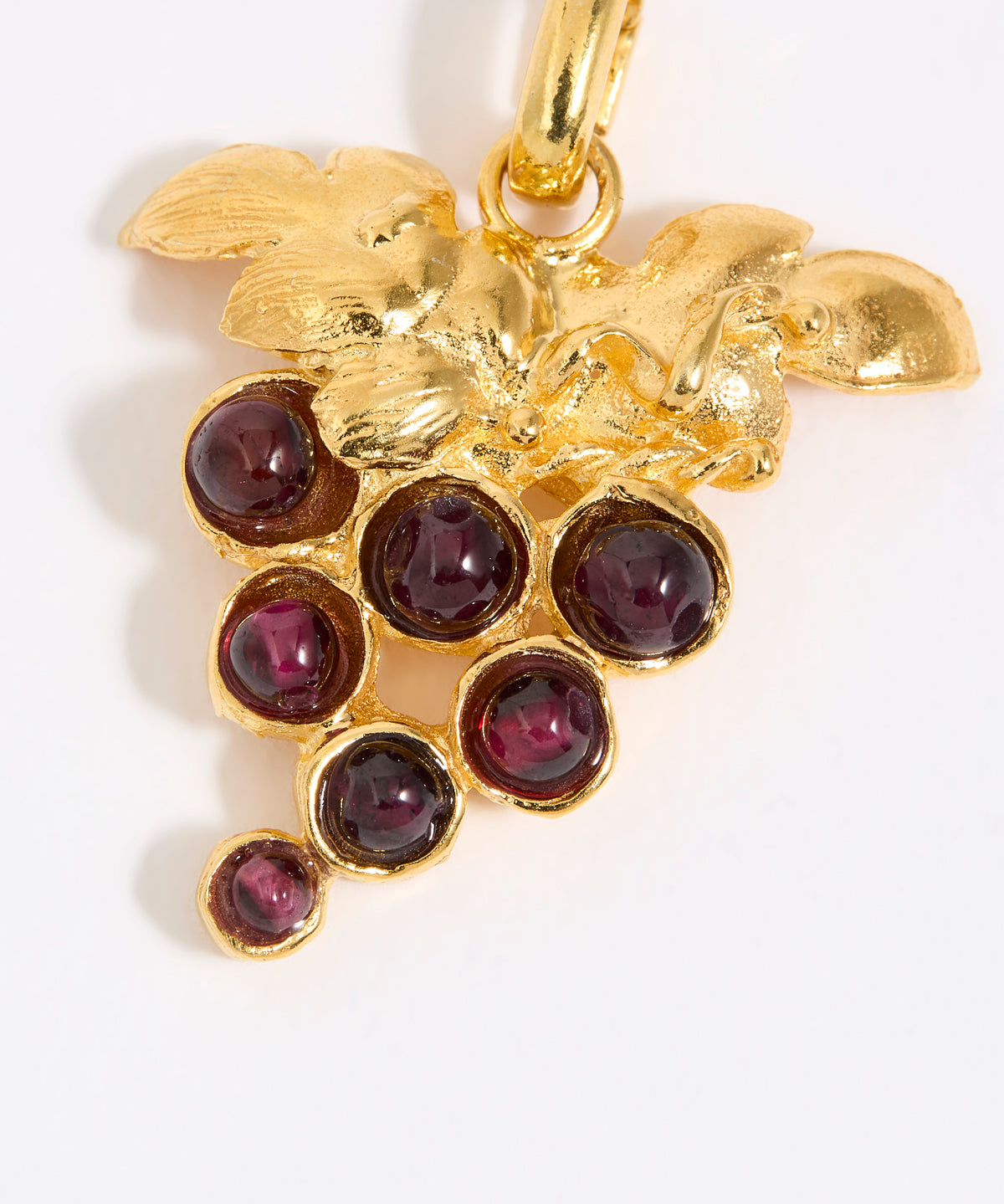 Gold pendant with red gemstones in the shape of a grape vine on a white background