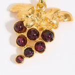 Gold pendant with red gemstones in the shape of a grape vine on a white background