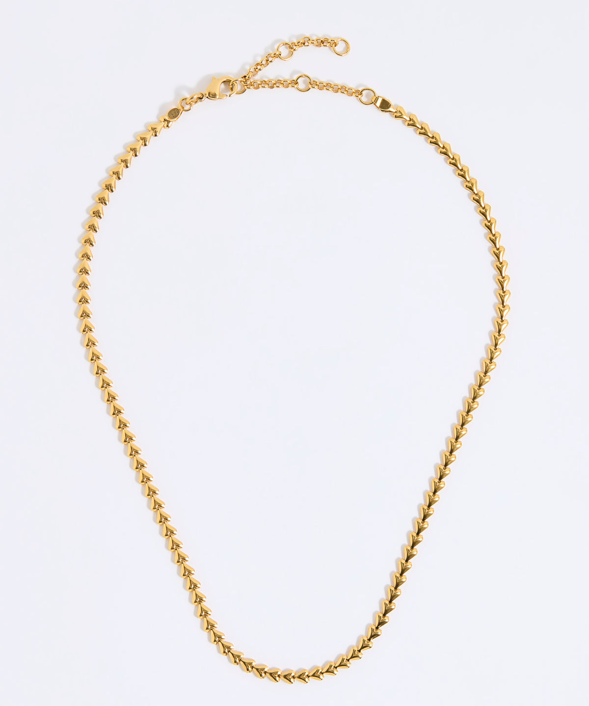 Gold coloured necklace made from small connecting hearts,  on a light gray background
