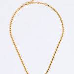 Gold coloured necklace made from small connecting hearts,  on a light gray background
