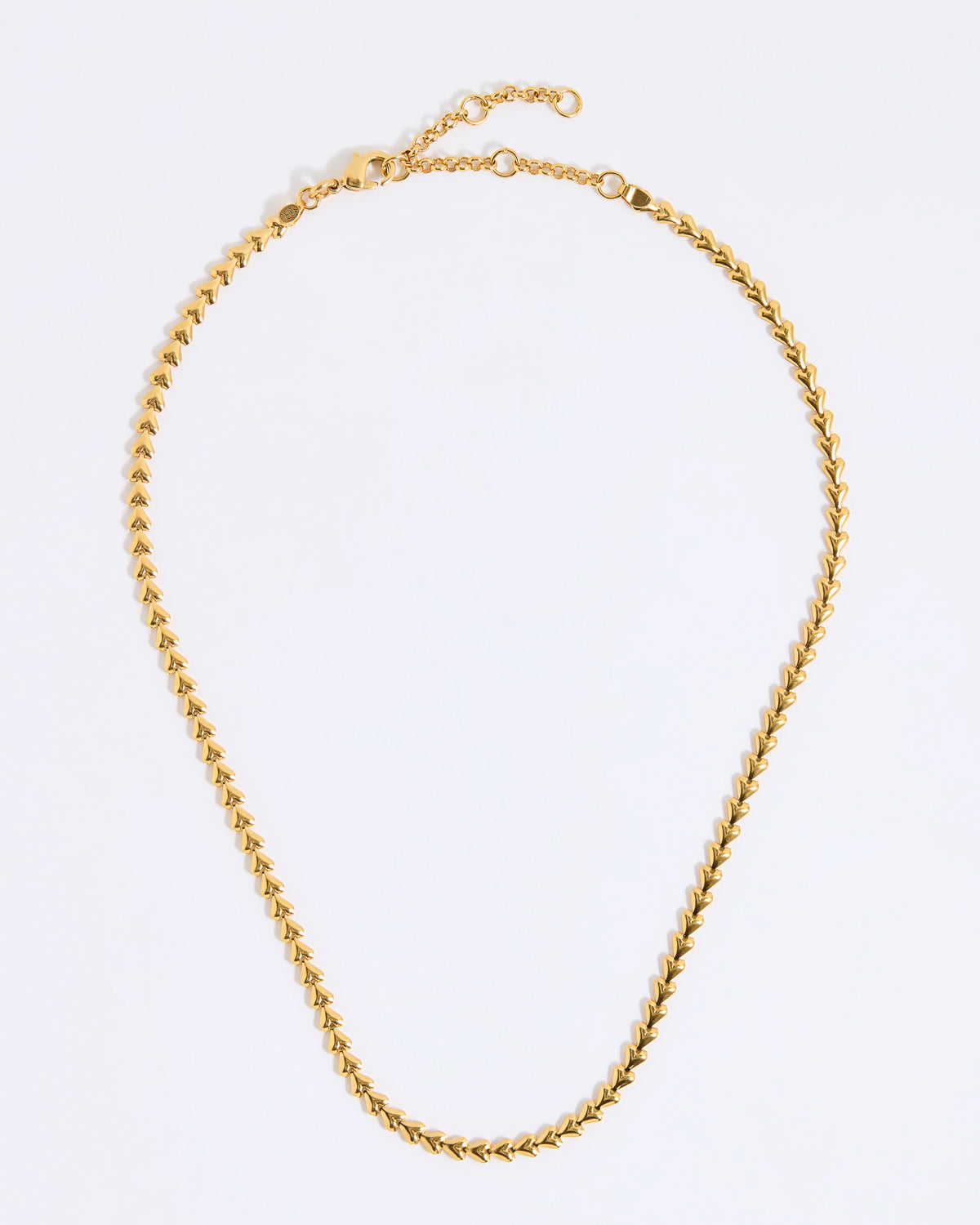 Gold coloured necklace made from small connecting hearts,  on a light gray background