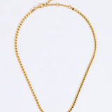 Gold coloured necklace made from small connecting hearts,  on a light gray background