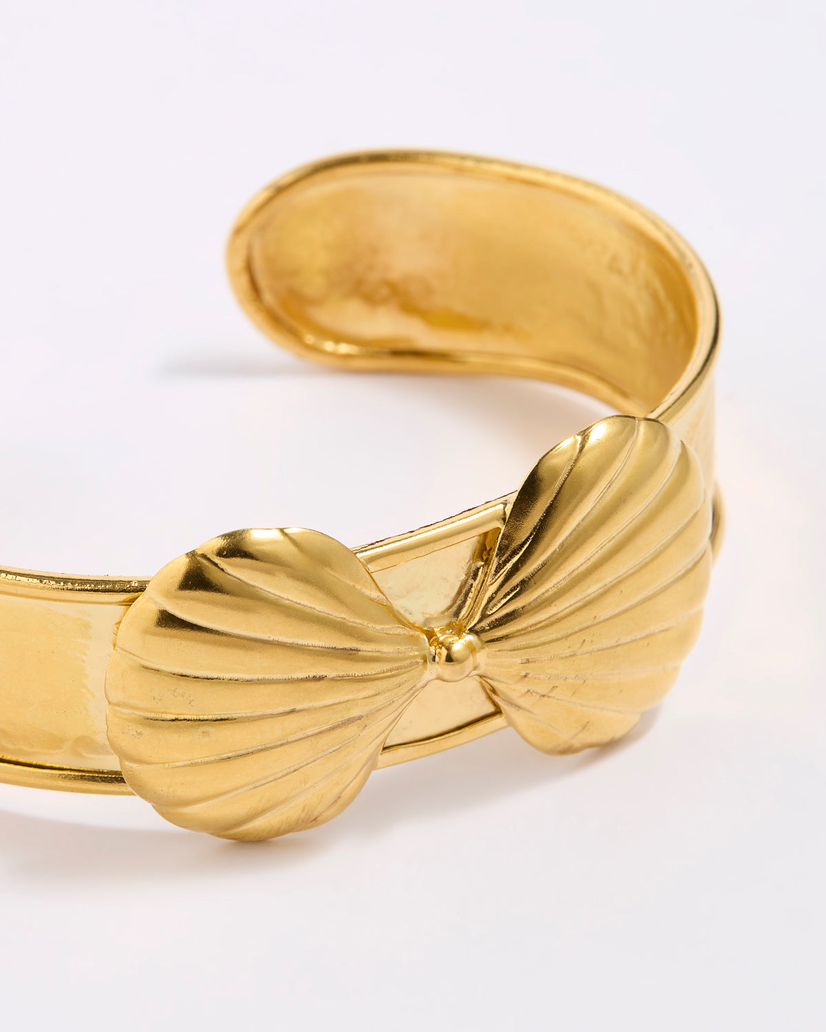 Gold coloured bracelet with shell design on a white background