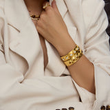 Person wearing gold jewelry including a bracelet and necklace, with a focus on the arm and hand.