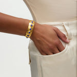 Gold bracelet with blue stones on a wrist against a neutral background