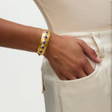 Gold bracelet with blue stones on a wrist against a neutral background