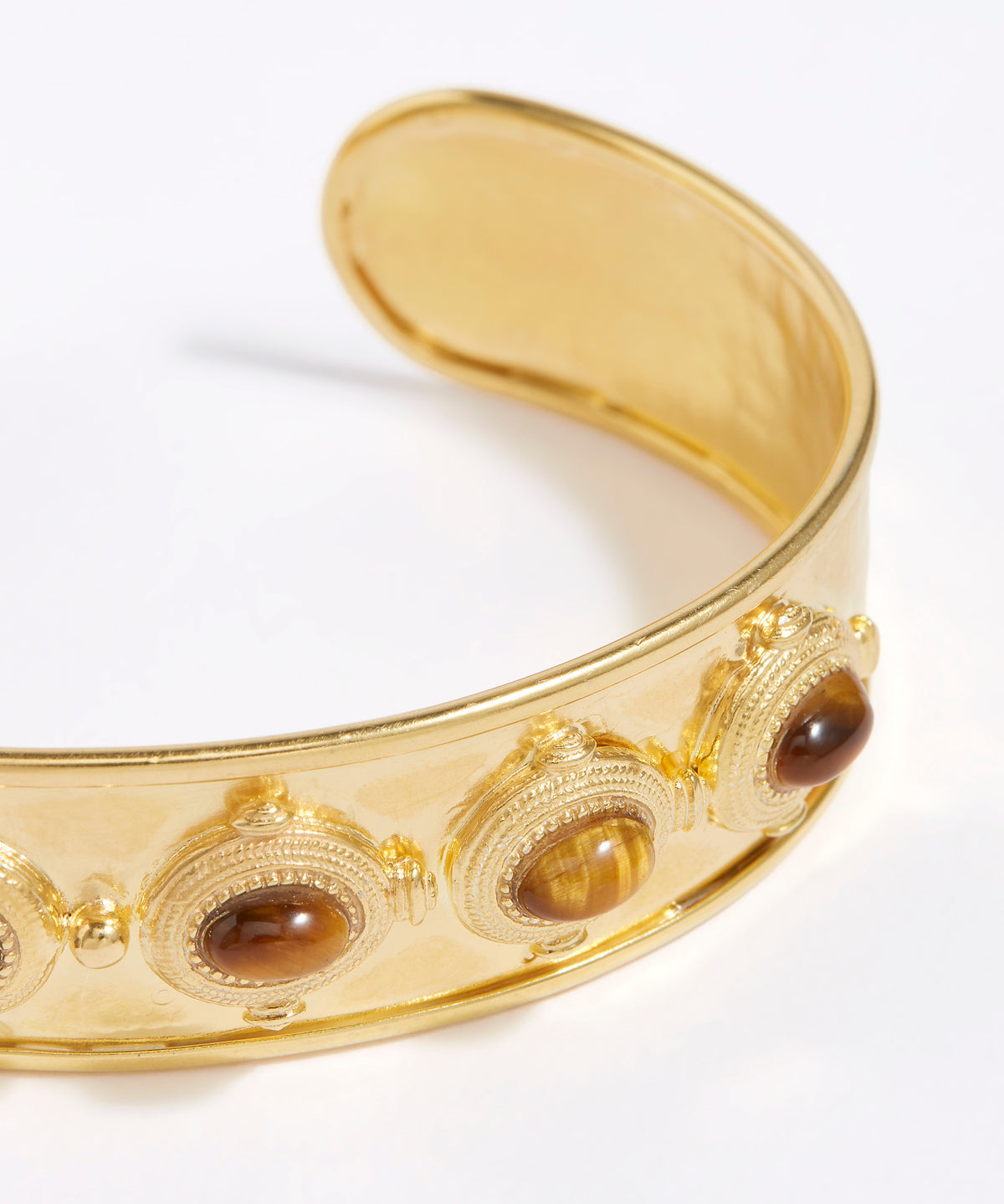 close up view of Gold cuff bracelet with embedded stones on a white background