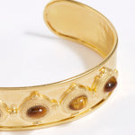 close up view of Gold cuff bracelet with embedded stones on a white background