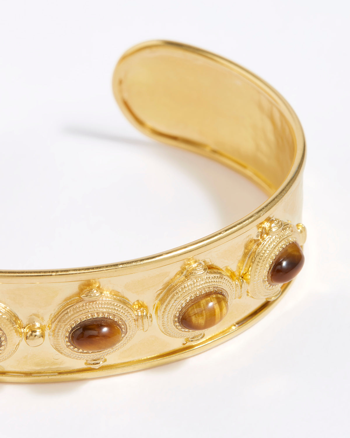 close up view of Gold cuff bracelet with embedded stones on a white background