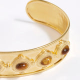 close up view of Gold cuff bracelet with embedded stones on a white background
