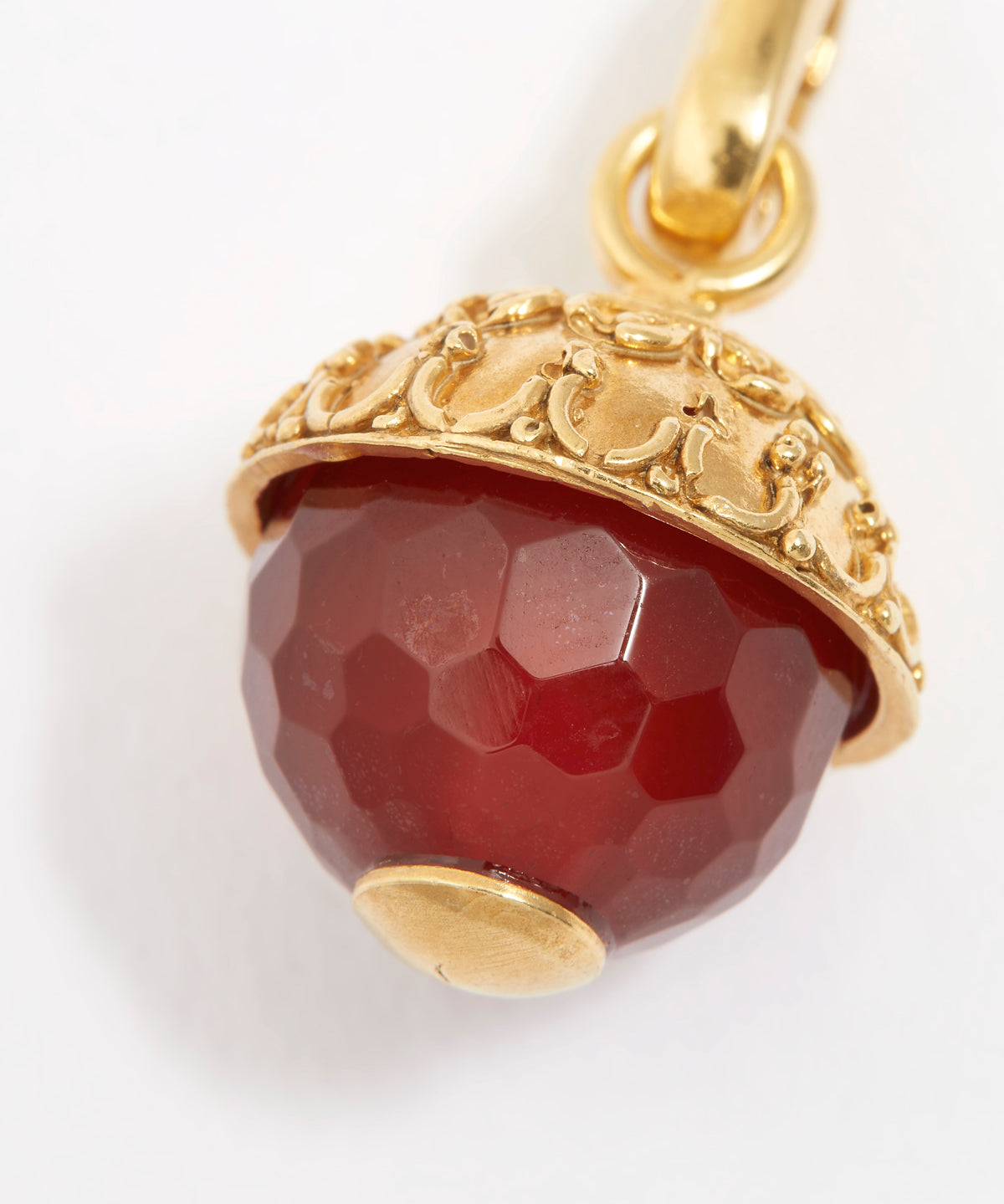 Gold pendant with a red gemstone on a white background