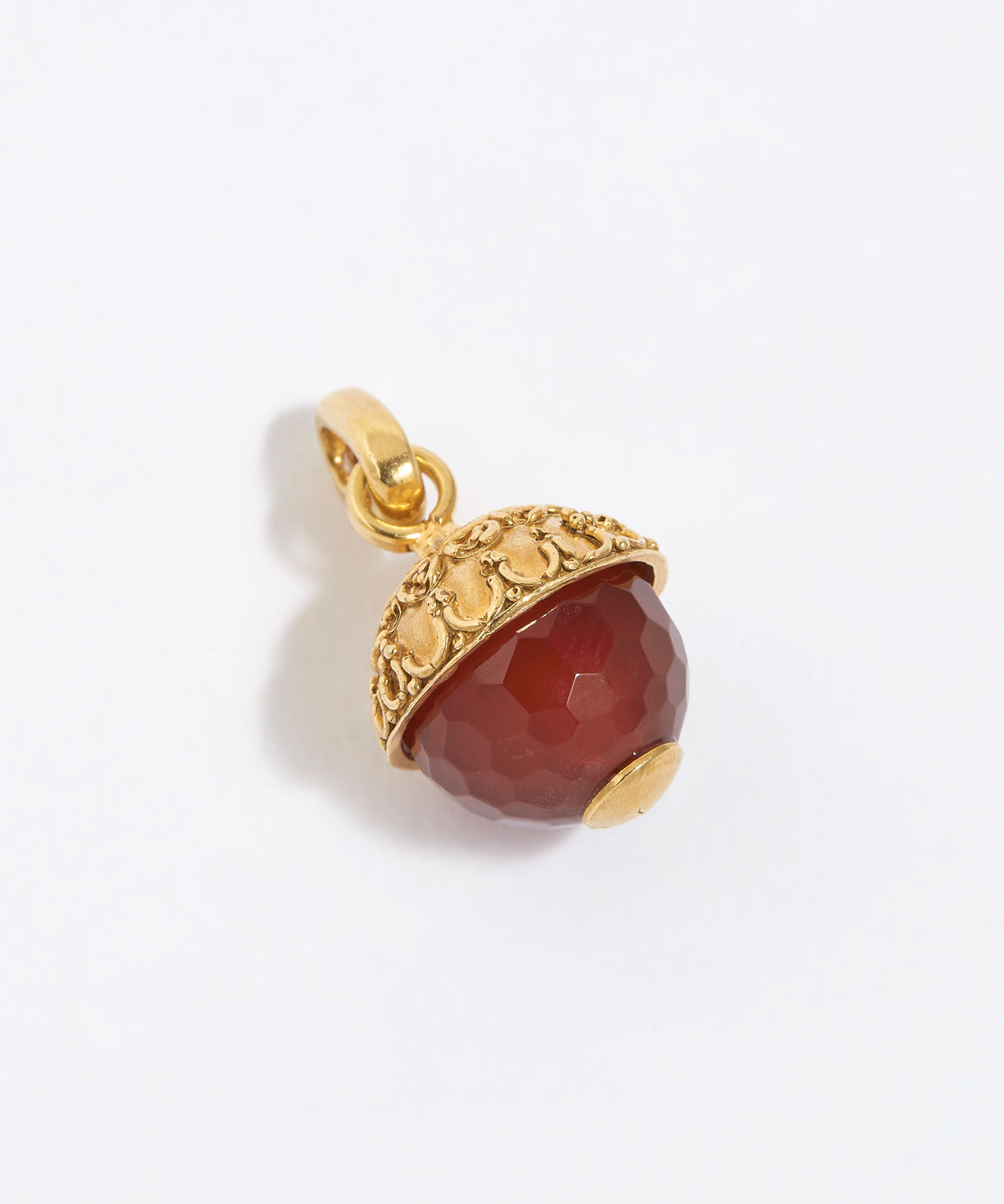 Gold pendant with a red stone on a white background