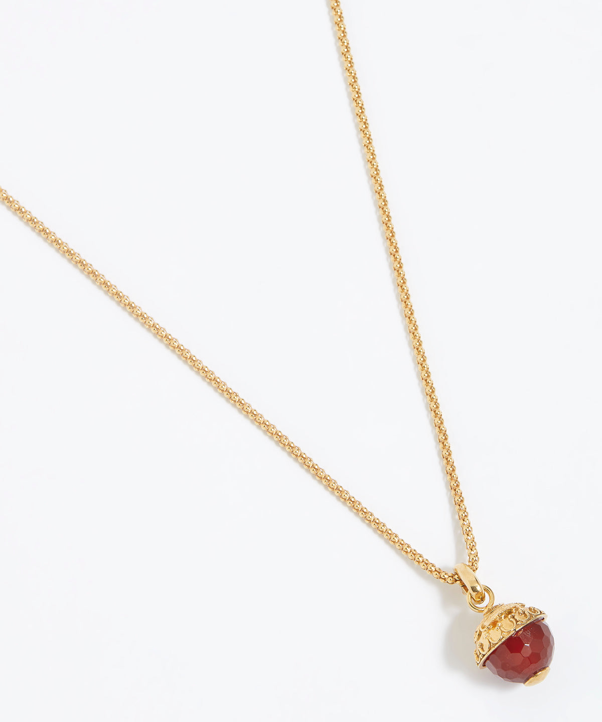 Gold necklace with a red pendant on a white background
