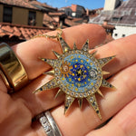 celestial design micro mosiac pendant being held in a hand up close 