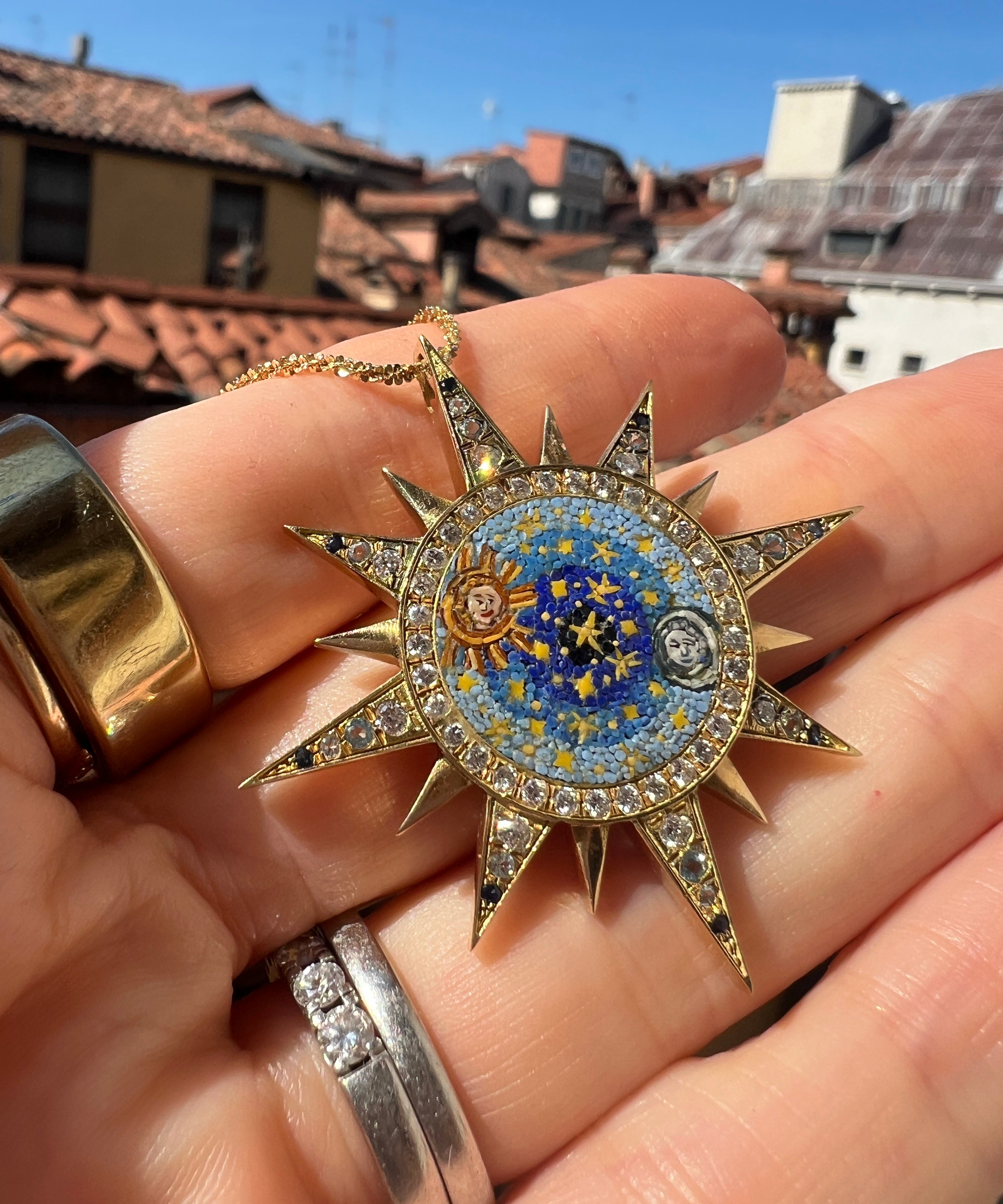celestial design micro mosiac pendant being held in a hand up close 