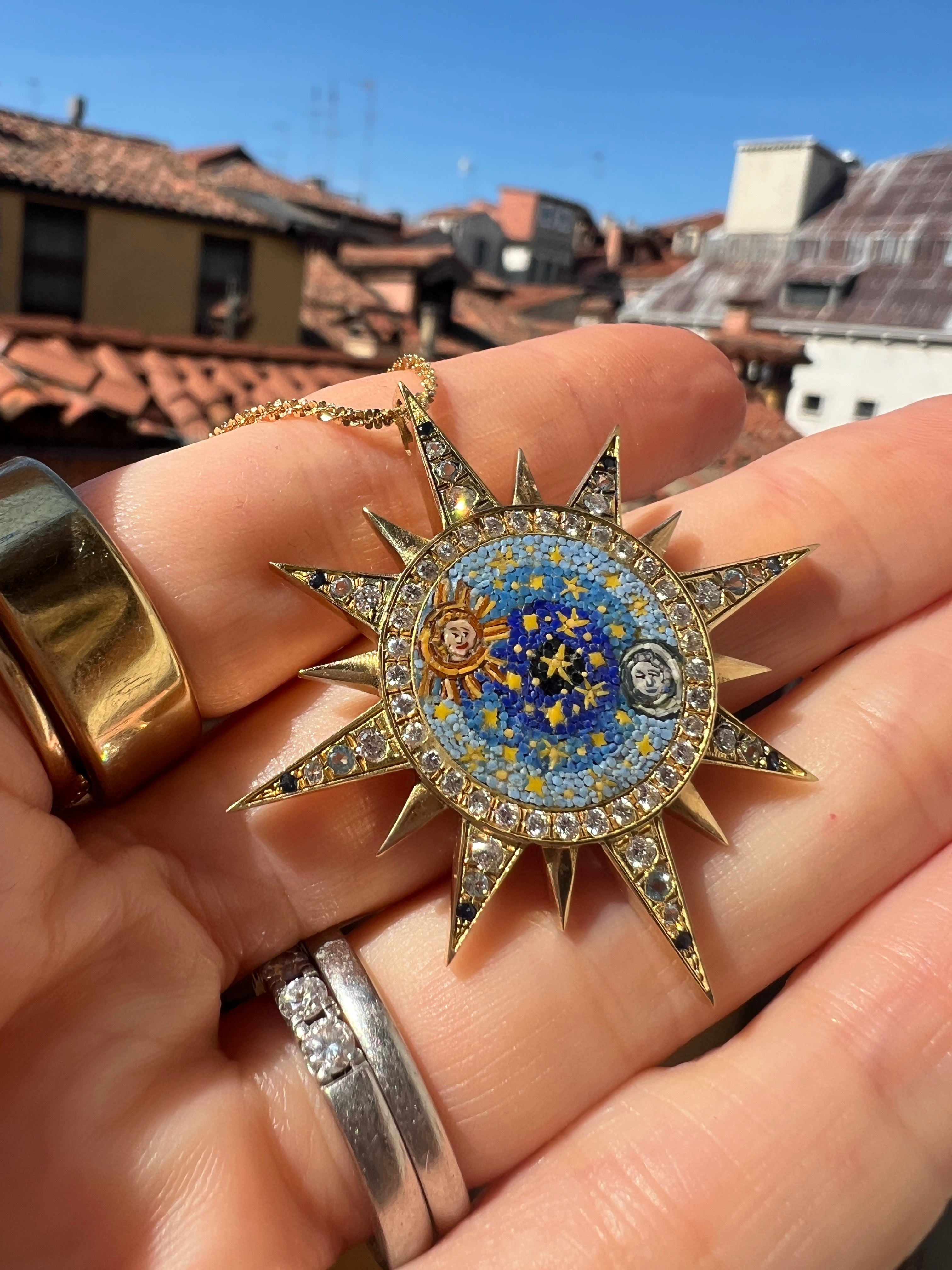 celestial design micro mosiac pendant being held in a hand up close 