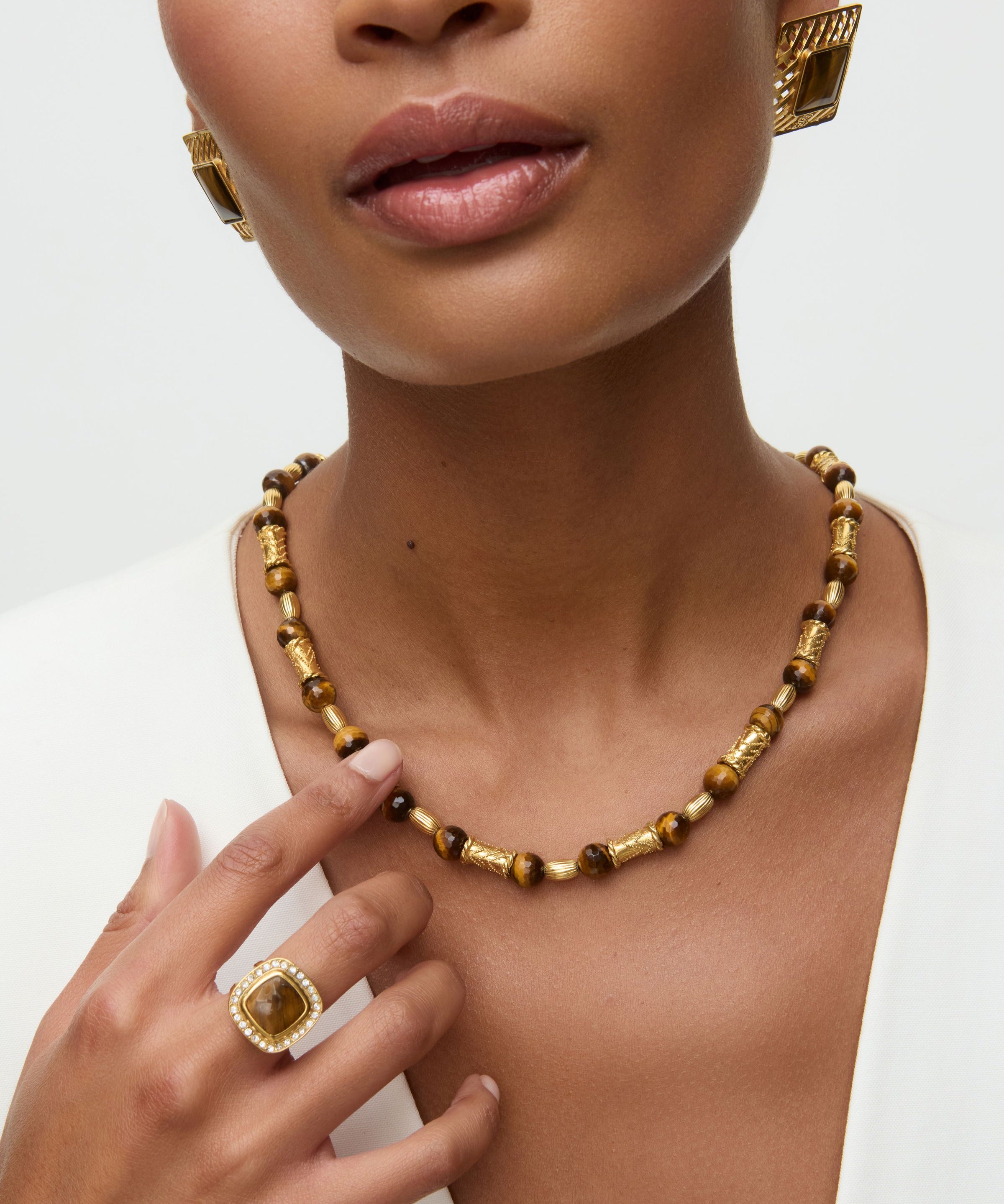 Close-up of a woman wearing a gold necklace and ring on a white background