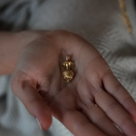Close up of a hand holding art deco gold charm for a charm necklace