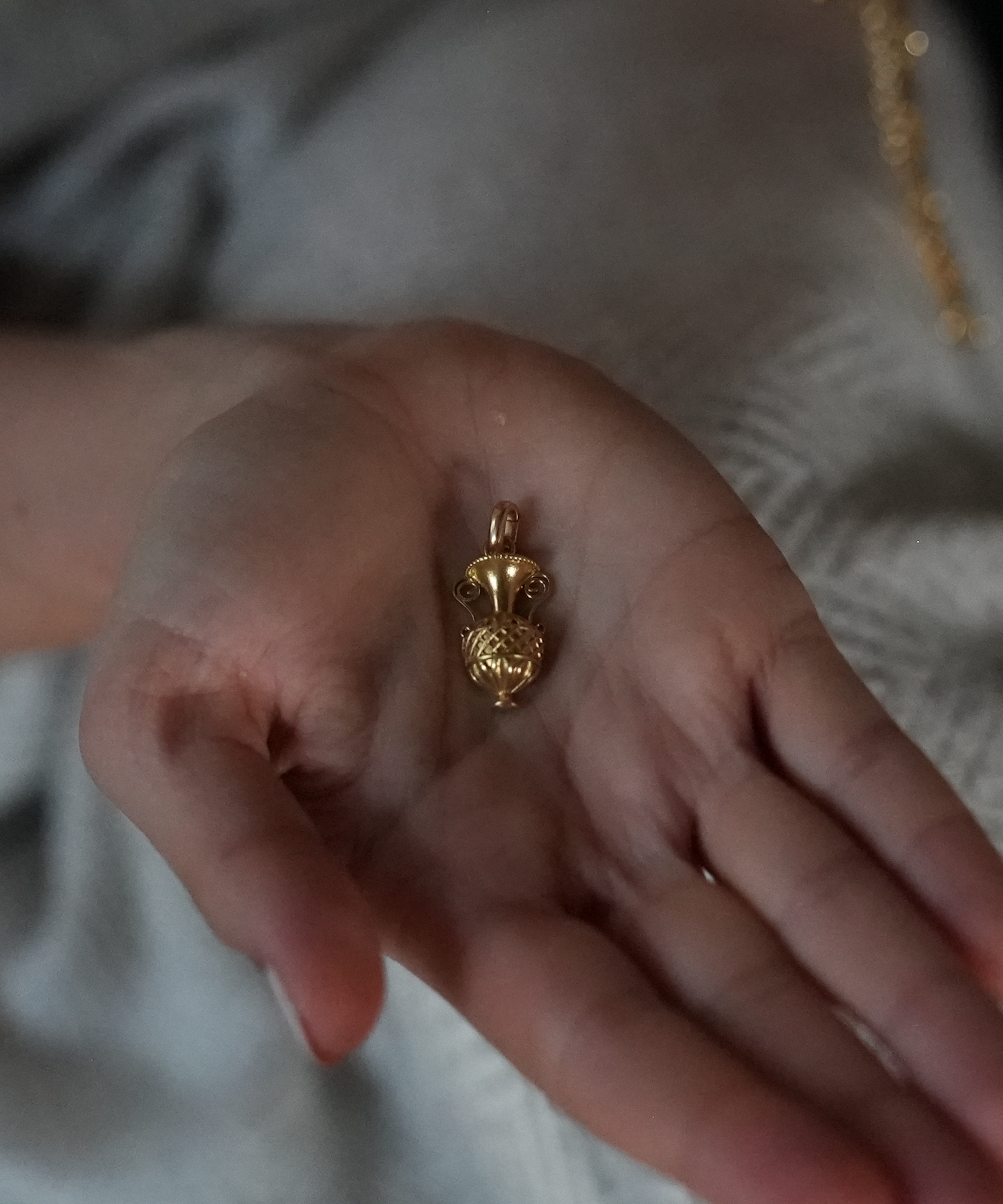 Close up of a hand holding art deco gold charm for a charm necklace