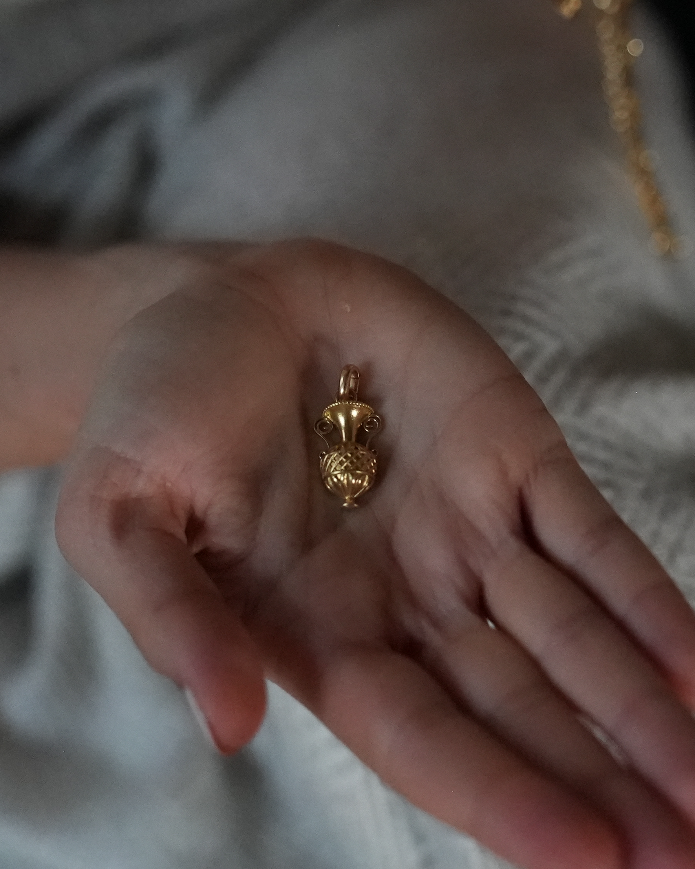 Close up of a hand holding art deco gold charm for a charm necklace