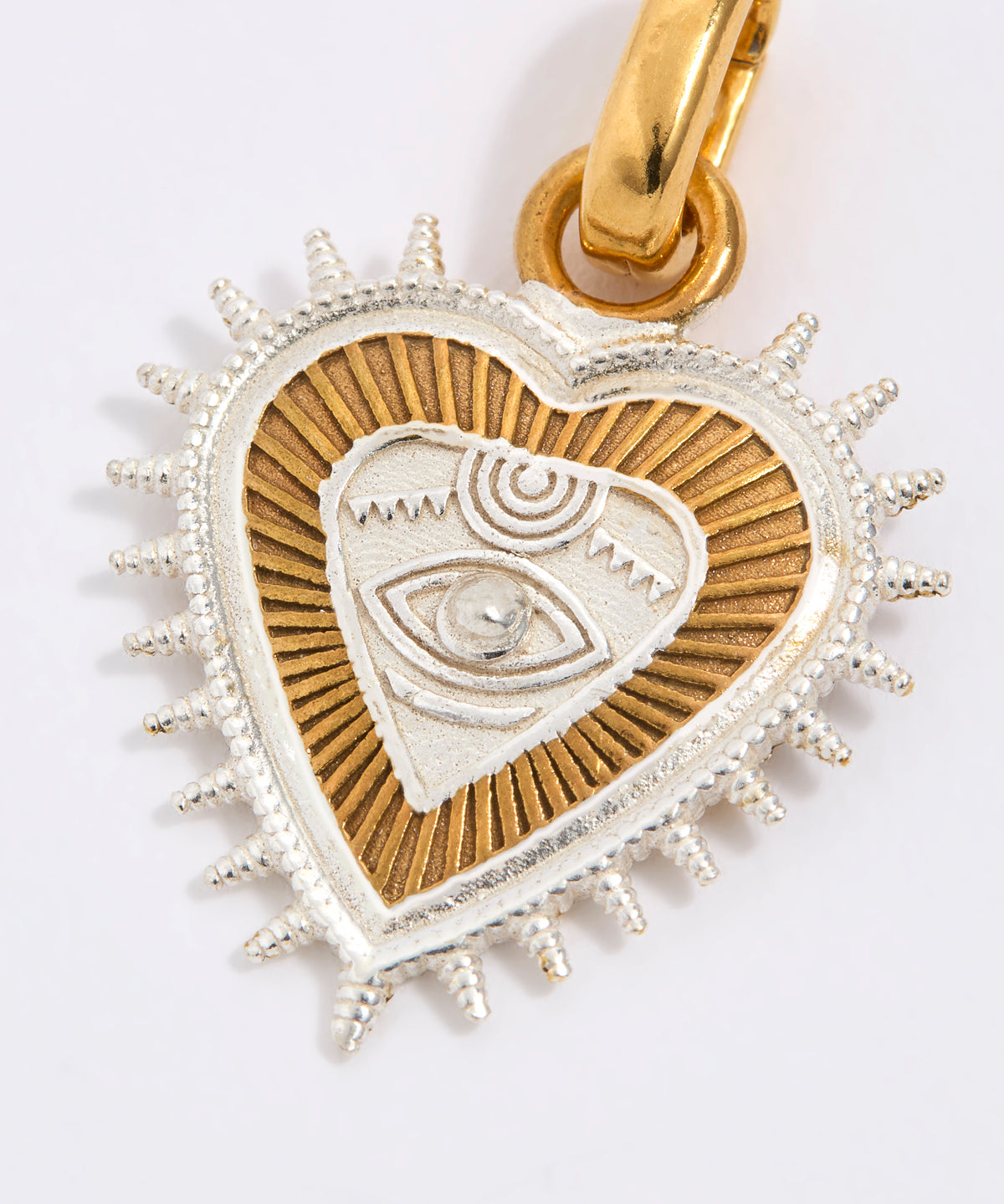 Heart-shaped pendant with eye design in gold and silver on a white background