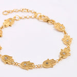 Gold bracelet with hamsa hand designs on a white background
