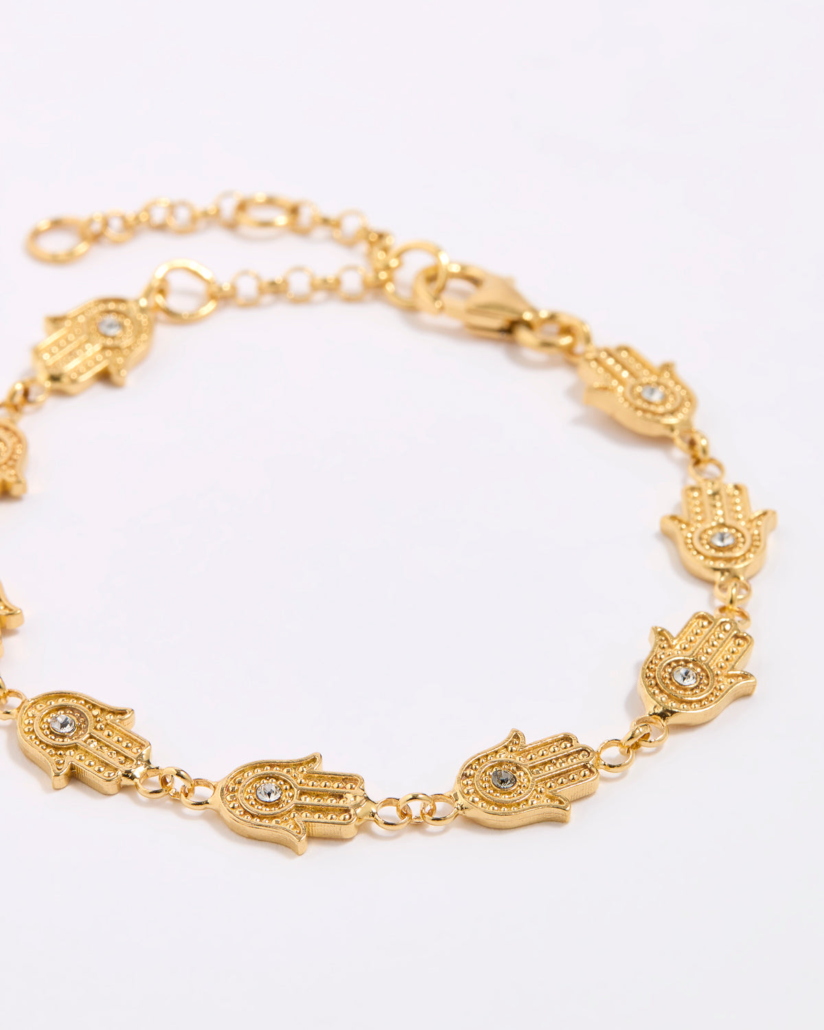 Gold bracelet with hamsa hand designs on a white background