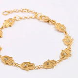 Gold bracelet with hamsa hand designs on a white background