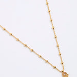Gold coloured necklace with a hamsa hand pendant on a white background