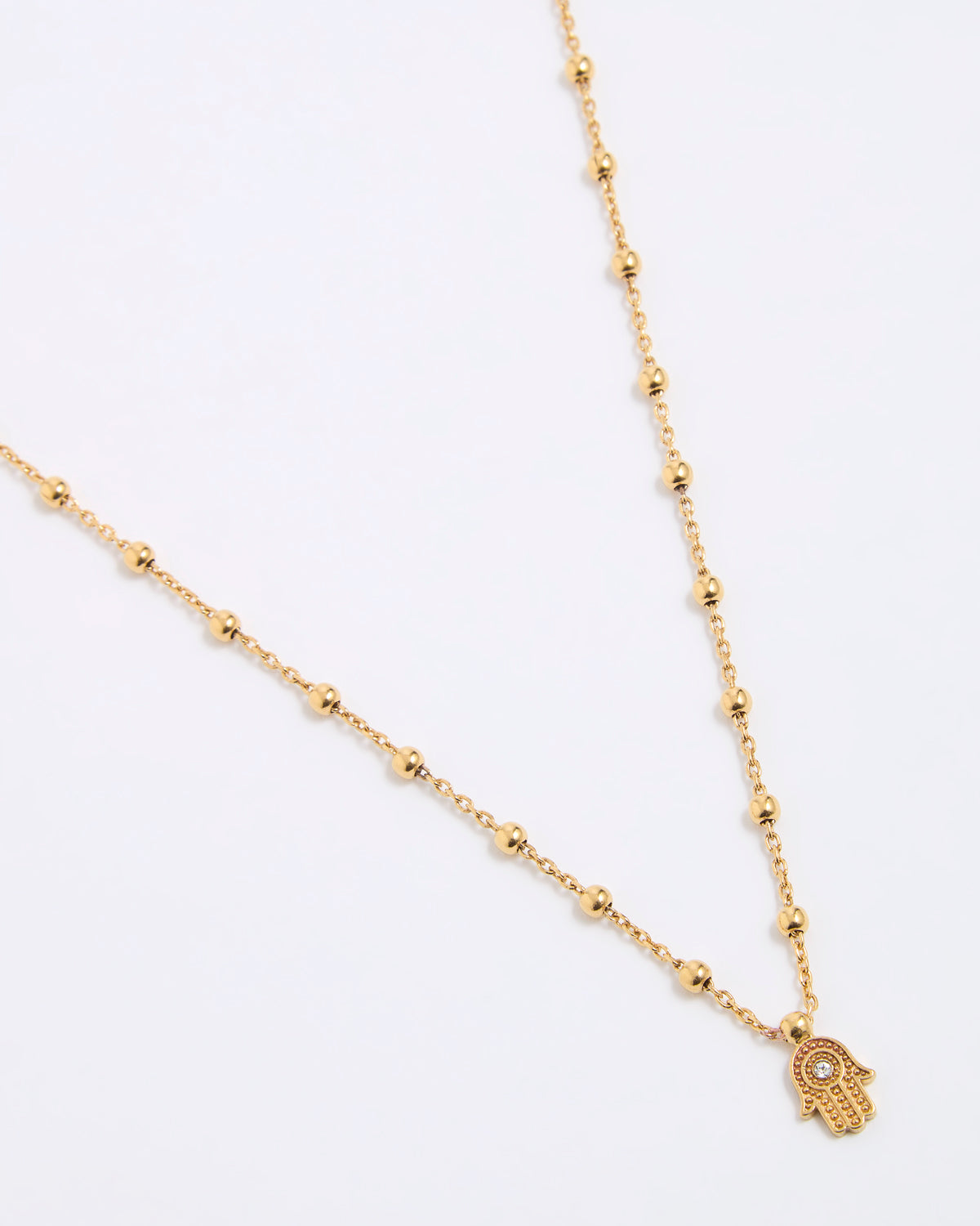 Gold coloured necklace with a hamsa hand pendant on a white background