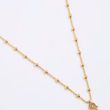 Gold coloured necklace with a hamsa hand pendant on a white background