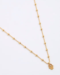 Gold coloured necklace with a hamsa hand pendant on a white background